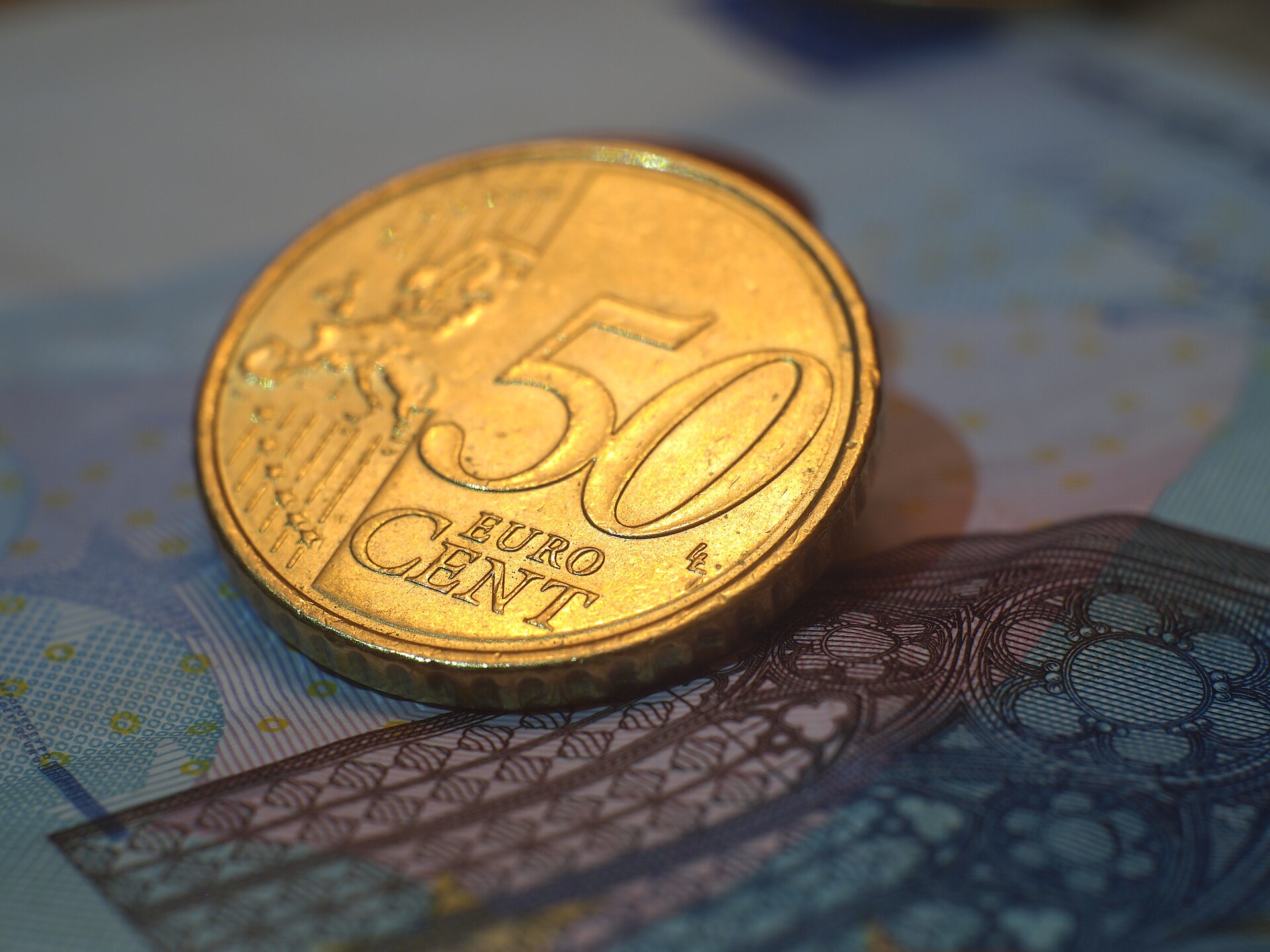 A fifty euro cent coin resting on euro banknotes